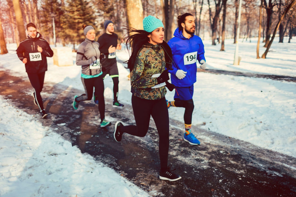 Runners running marathon in the city. They are running trough the city park. Wearing numbers on their sport clothes.