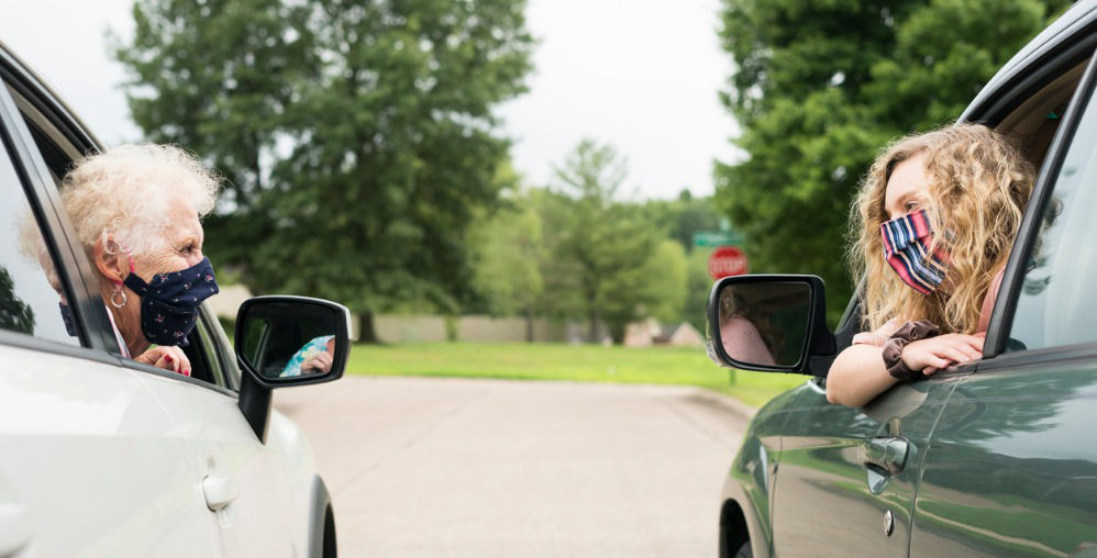 Women masked talking from cars