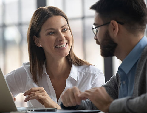 Close up happy smiling businesswoman listening businessman talking in boardroom at meeting. Leader presenting new business concept for colleague discuss. Team together using laptop for teamwork.