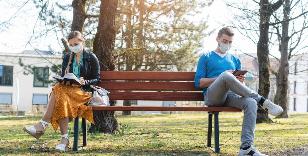 Woman and man in social distancing bench 