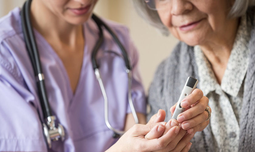 Nurse giving blood sugar test to patient in home