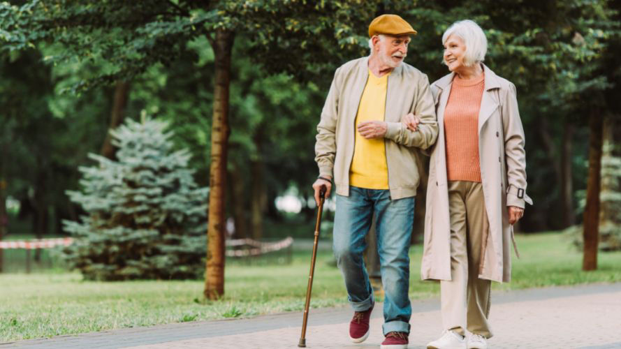 pareja-mayor-feliz-caminando-en-el-parque-con-bastón