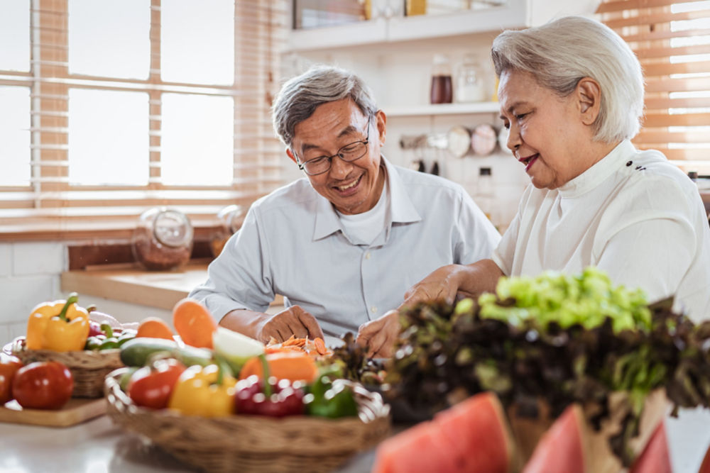 Pareja asiática de adultos mayores adora cocinar juntos en la cocina con felicidad