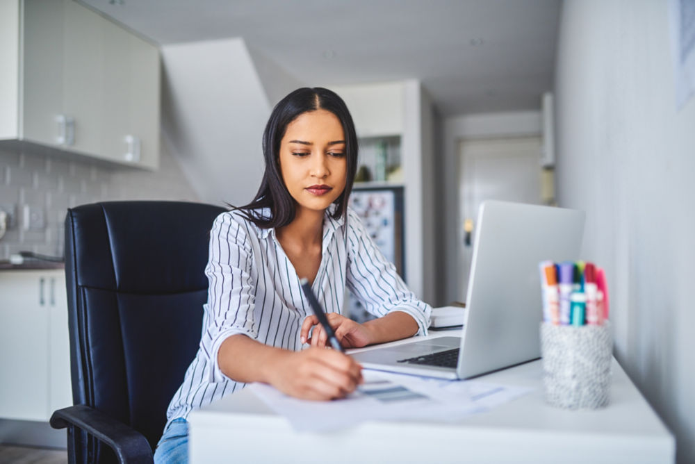 Fotografía recortada de una joven empresaria sentada mientras calcula sus finanzas a solas en casa