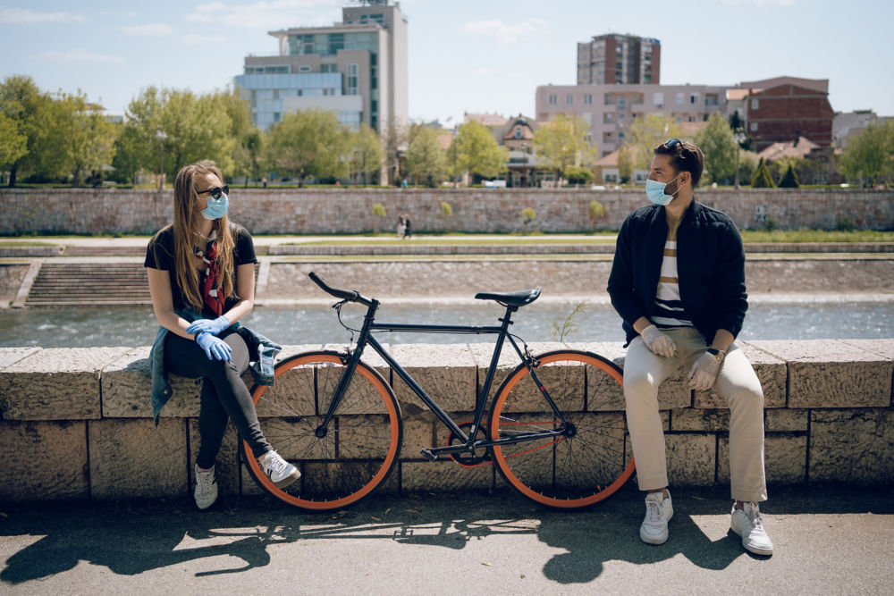 Pareja joven intentando mantener su relación durante una pandemia. Ellos disfrutan de su amor, aplican todas las medidas de protección y usan máscaras y guantes protectores.