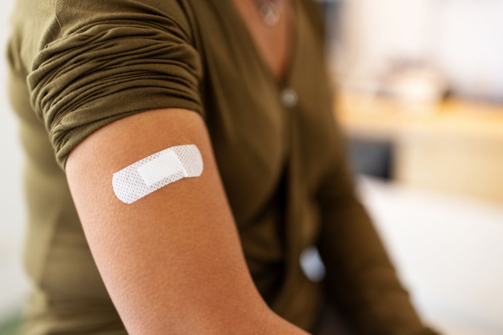 Vendaje en el brazo de una mujer después de recibir la vacuna. Primer plano de una paciente con vendaje en la mano después de recibir la inyección.