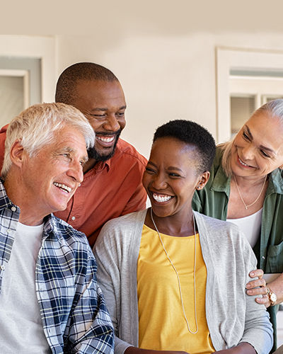 Cheerful friends sitting in courtyard enjoying the afternoon together. Group of four mature people sitting outside home and laughing. Happy senior man and old woman enjoying with mature african couple.