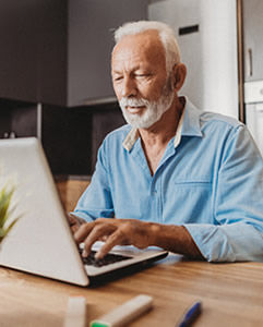 Hombre presentando una reclamación de salud mental en una computadora portátil en casa.