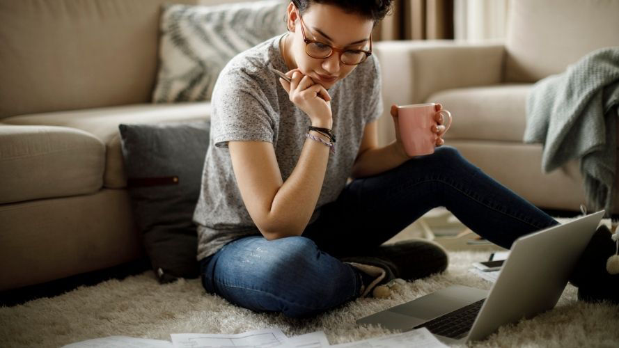 Mujer en casa con una computadora portátil revisando los beneficios del seguro de salud