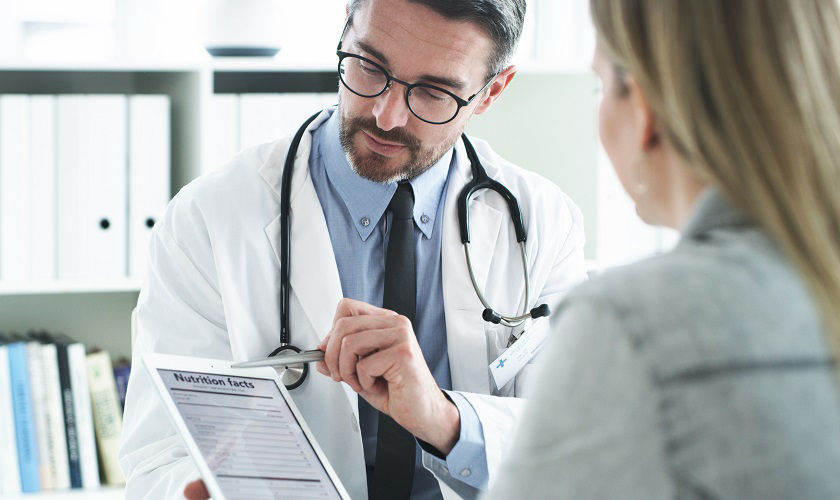 Cropped shot of a handsome middle aged male doctor explaining a nutritional facts table on a digital tablet to a female patient in his office