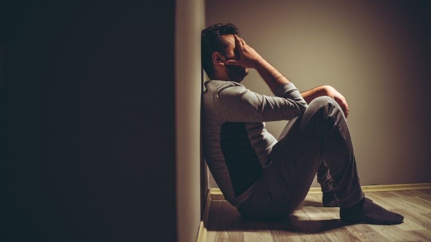 stressed-man-with-head-in-hands-leaning-on-wall