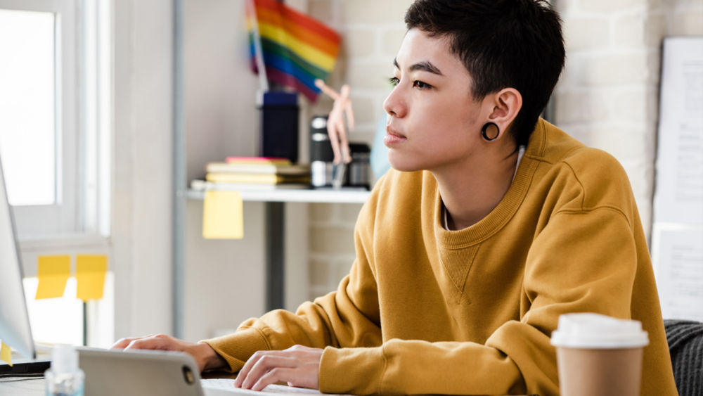 Young Asian tomboy woman in casual attire working from home in living room