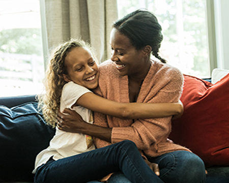 Mother talking with young daughter on sofa