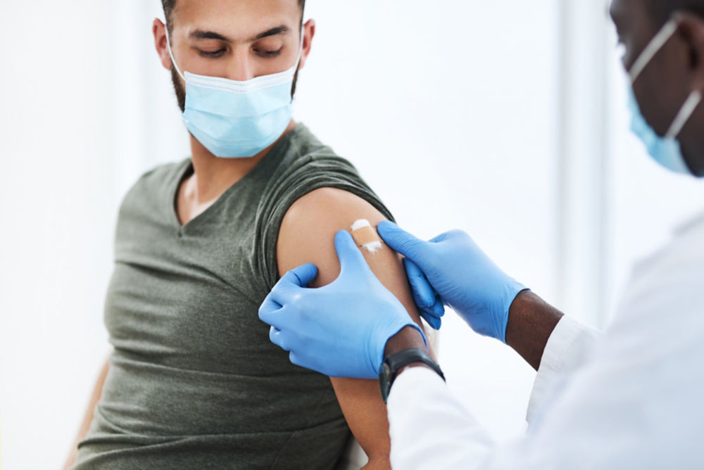 Shot of a doctor applying a band aid after injecting a patient in his arm during a consultation at a clinic