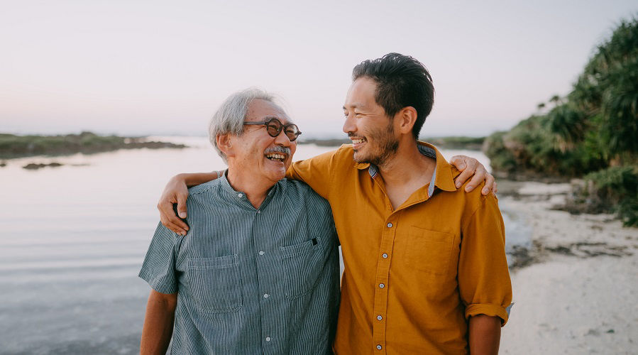 年迈的父亲和长大成人的儿子在日落时分在海滩上度过美好时光（日本鹿岛阿玛米群岛的基凯岛）