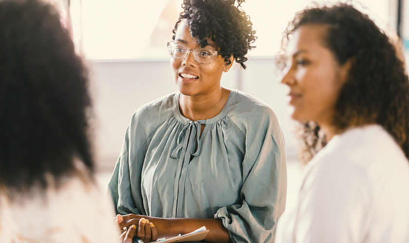 During group therapy, two women listen attentively as a third, unrecognizable woman speaks.