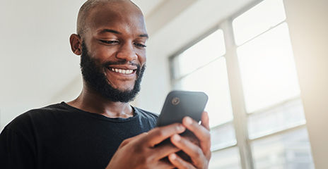 Un hombre feliz mira su teléfono móvil