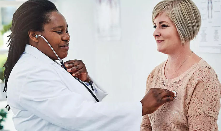 female doctor examining female patient with stethoscope