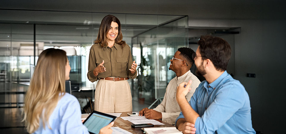 Happy middle aged business woman executive ceo leader discussing project management planning strategy working with diverse colleagues company team at office corporate board group meeting.