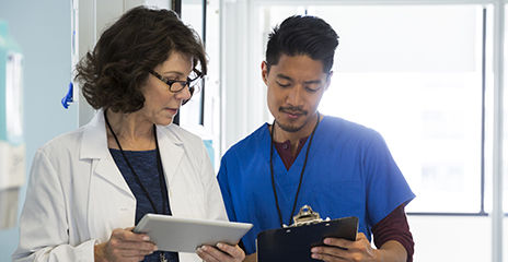 health care providers talking and looking at clipboard and tablet