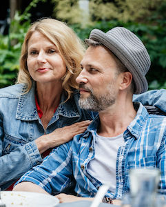 A couple sitting cloesly together at a family barbecue in a courtyard.