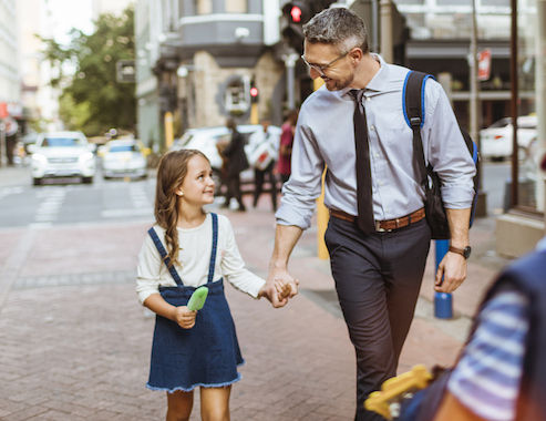 Primer plano de un padre acompañando a sus hijos a casa desde la escuela