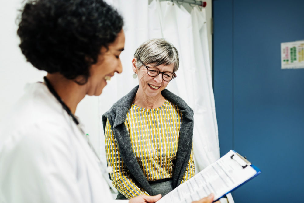 Un médico clínico repasando los resultados de una prueba con un paciente anciano en el hospital.