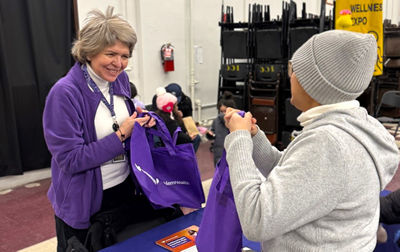 An EmblemHealth representative shares resources and giveaways with a community member at a Three Kings Day event in the Bronx. 