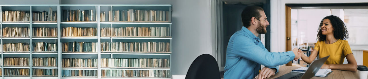 dos personas estrechándose la mano frente a una computadora