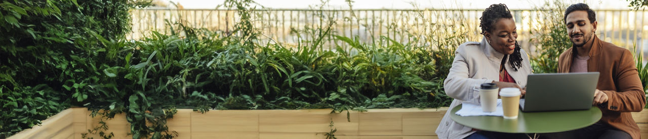 两个人坐在外面，拿着笔记本电脑