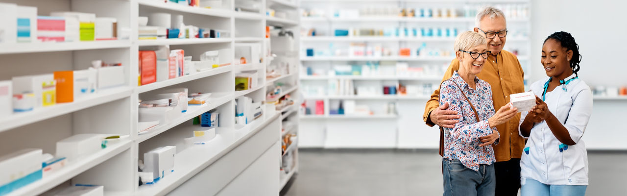 A Pharmacist advising senior couple in choosing medication in drugstore.