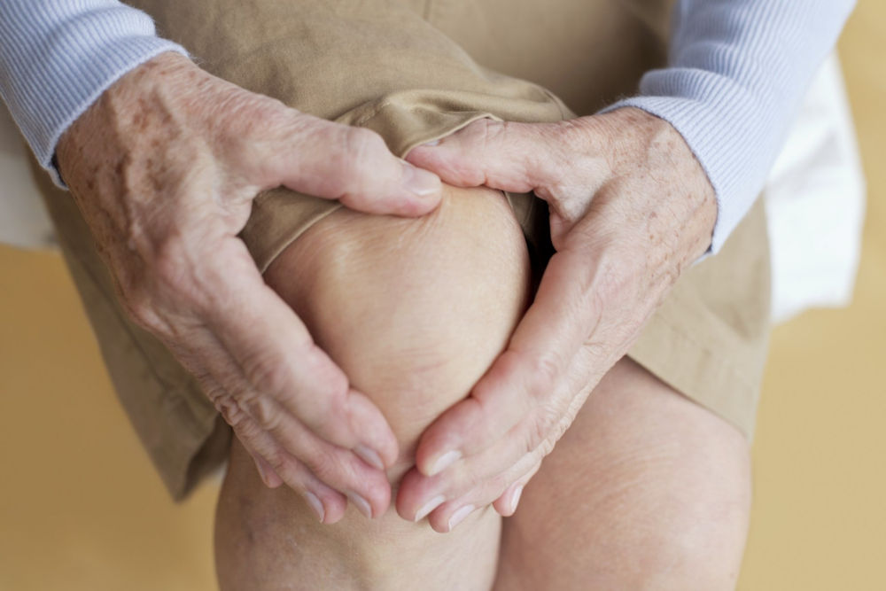 MODELO PUBLICADO. Adulta mayor sosteniendo su rodilla adolorida.