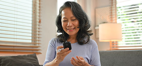 Female is smiling and holding a glucometer