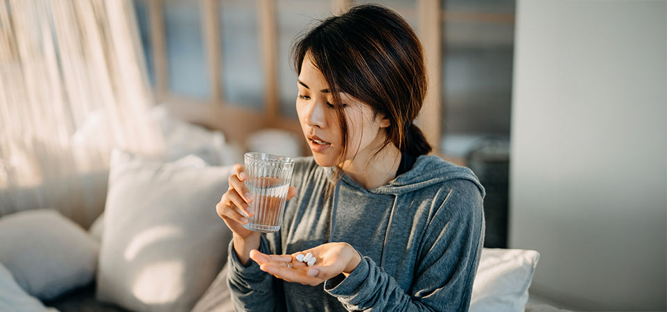  woman sitting on bed and taking pills