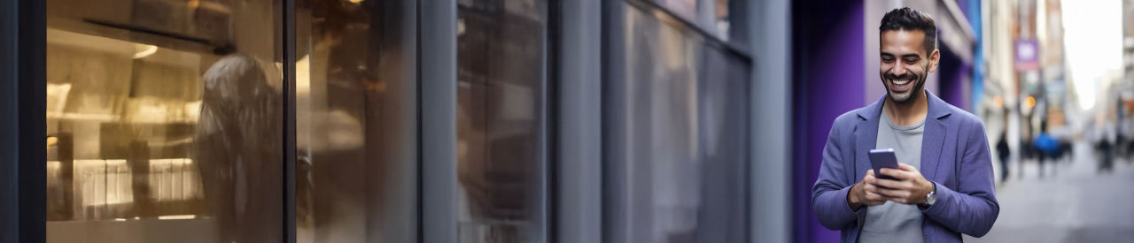 man looking at phone and smiling outside 