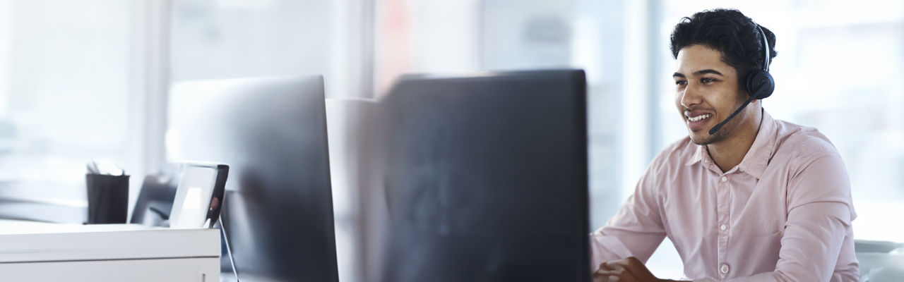 sales agent with headphones at computer