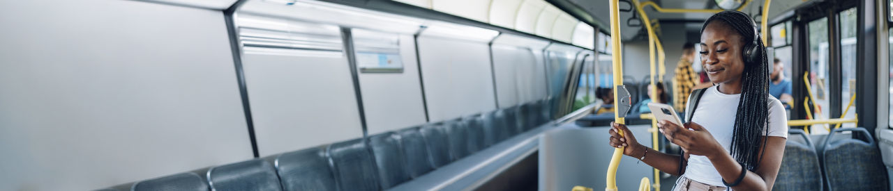 person with headphones looking at phone on subway