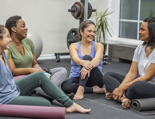 Un pequeño grupo de personas felices sentadas en un círculo sobre colchonetas de yoga 