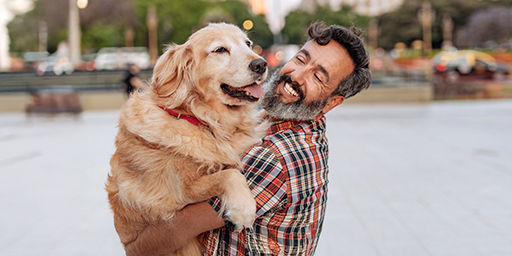 man smiling and holding a big dog