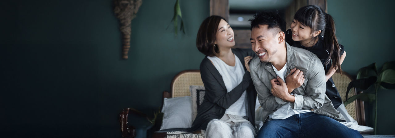 young family sitting on couch and laughing 