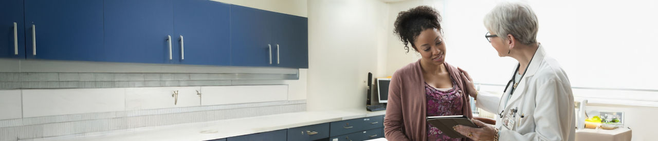 Gynecologist with digital tablet comforting pregnant patient