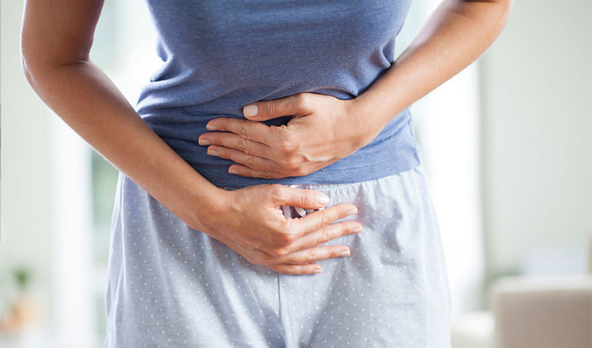 Young woman having painful stomach ache. Chronic gastritis. Stomach or menstrual cramps. Abdomen bloating concept.