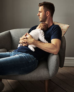 Fotografía de una adorable bebé durmiendo en el pecho de su padre en casa