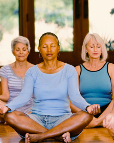 Three females are meditating in a meditation hall.