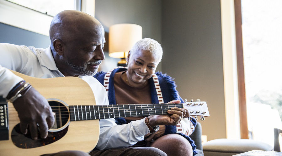 Senior man playing acoustic guitar for his wife at home