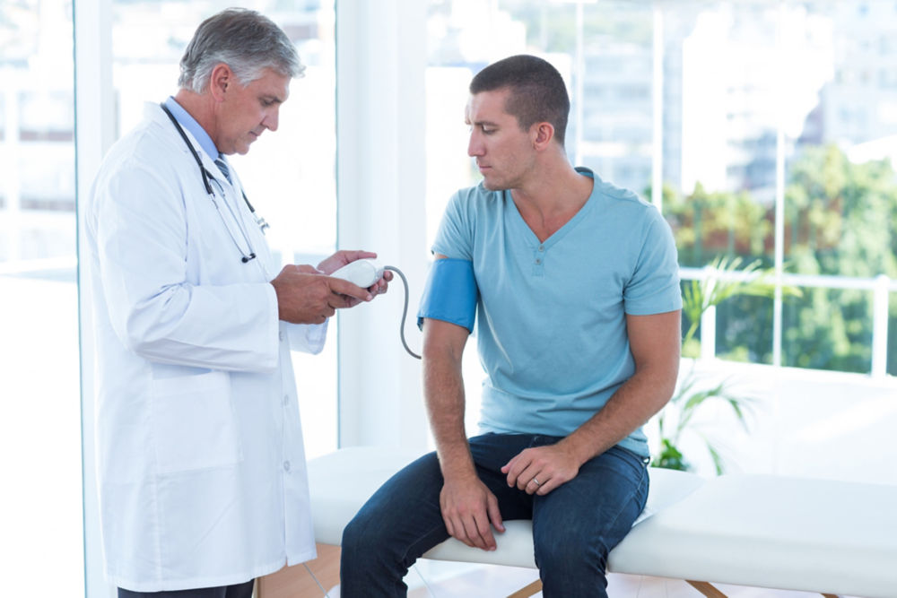 Doctor examining his patients blood pressure in medical office