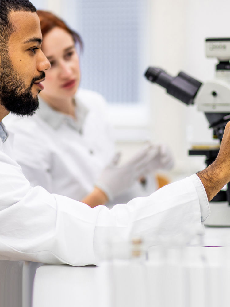 Man looking through microscope with woman looking over