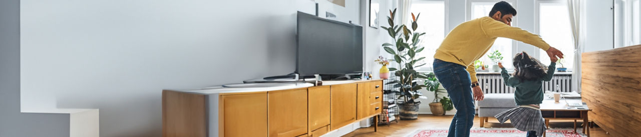 father dancing with young daughter in living room 