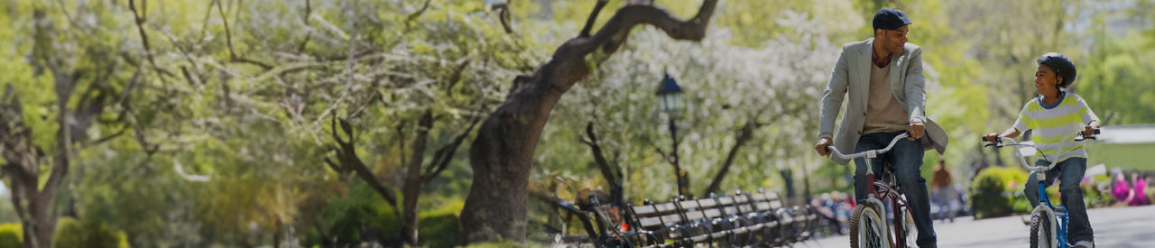 father and son riding bikes in the park 