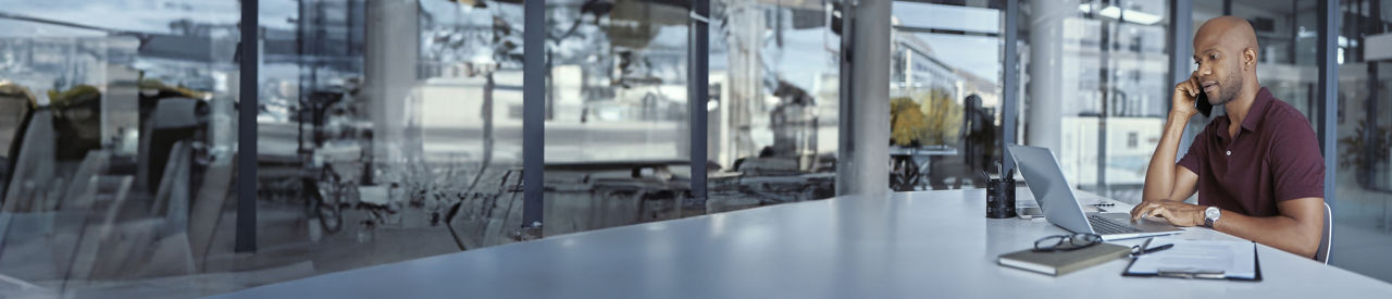 person holding cell and looking at laptop